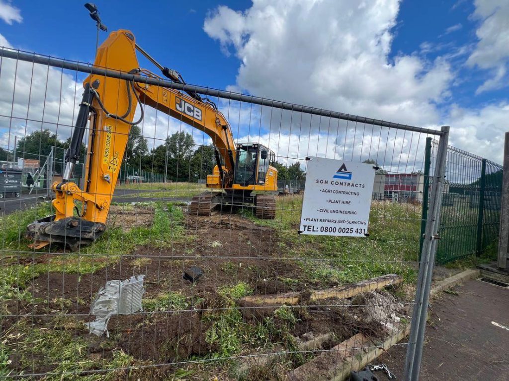 Excavator working at fenced construction area