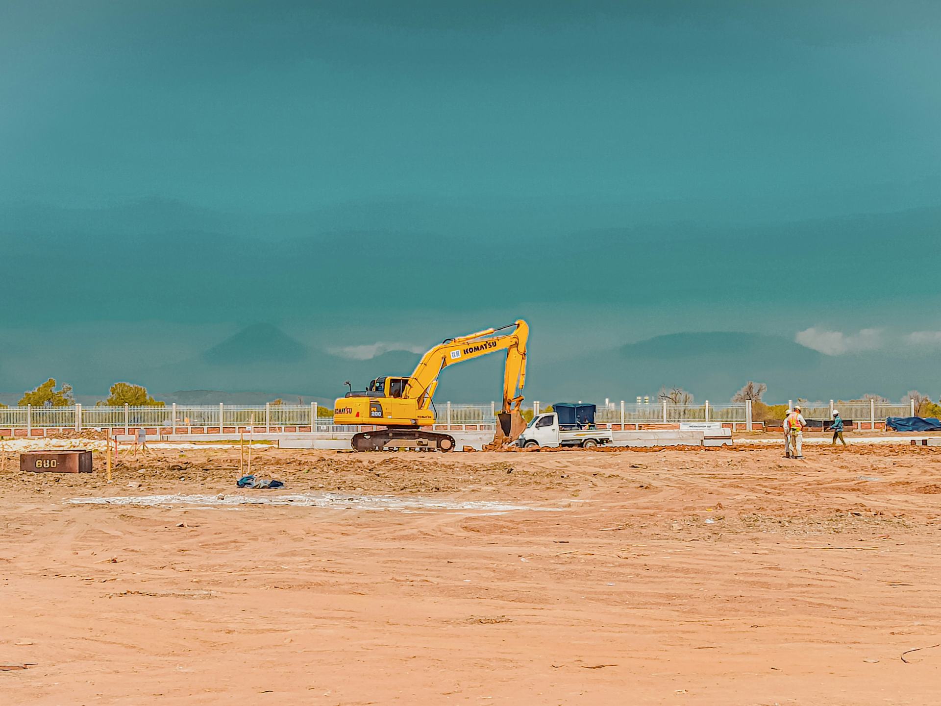 Excavator and workers on flat terrain