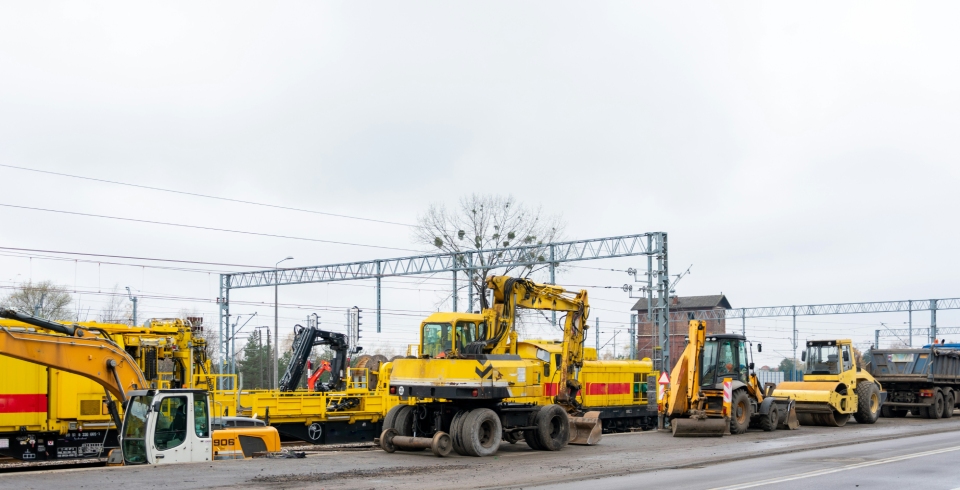 Line of construction vehicles near train tracks